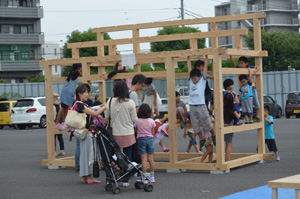 実演ショーで組み立てられた家の枠組みで遊ぶ子どもたち